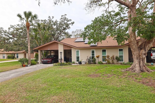 single story home with a front yard, concrete driveway, a carport, and roof mounted solar panels