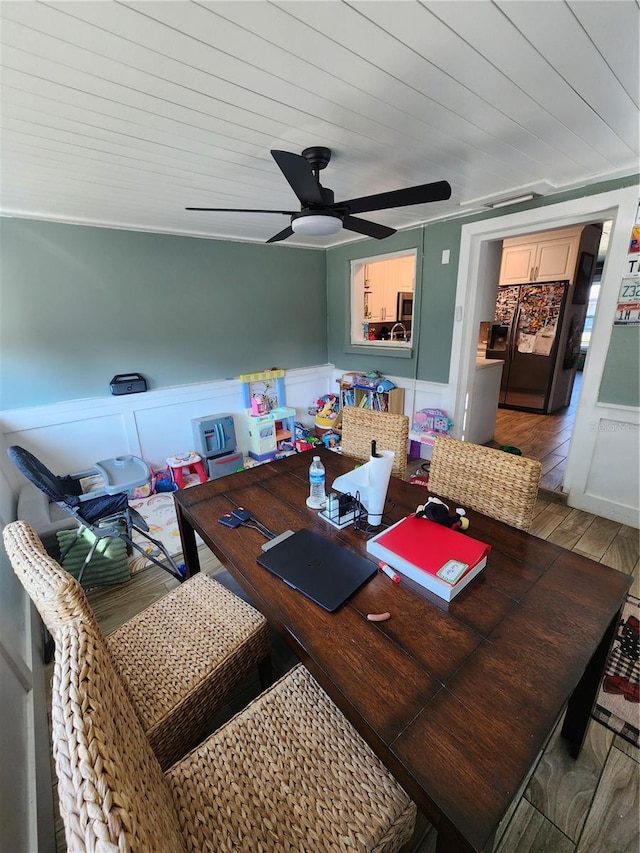 dining space with wood ceiling, wood finished floors, a wainscoted wall, and ceiling fan