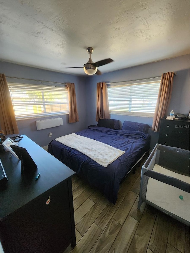 bedroom with a textured ceiling, wood finished floors, and ceiling fan