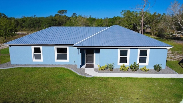 single story home with a front yard, metal roof, and stucco siding