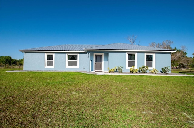 ranch-style home with metal roof, a front yard, and stucco siding