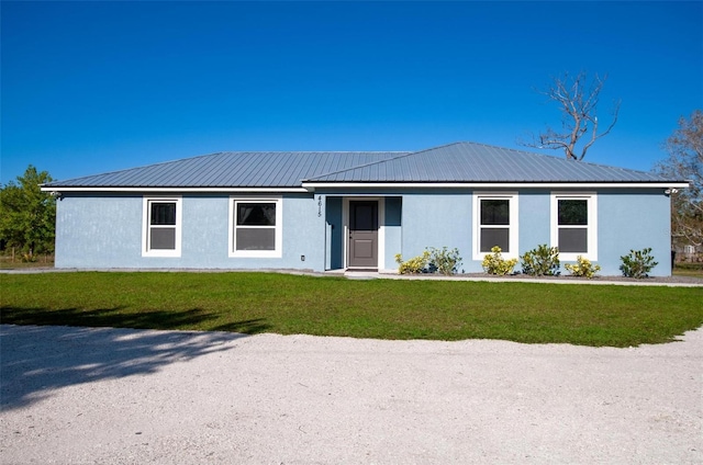 ranch-style home featuring stucco siding, metal roof, and a front lawn