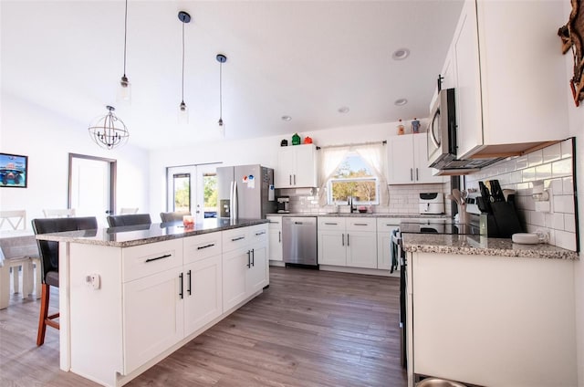 kitchen with light wood-type flooring, a kitchen breakfast bar, a center island, stainless steel appliances, and decorative backsplash