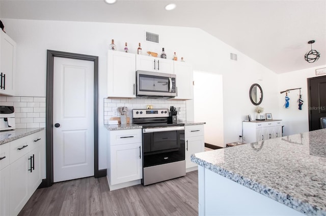 kitchen featuring light wood finished floors, visible vents, lofted ceiling, appliances with stainless steel finishes, and white cabinetry