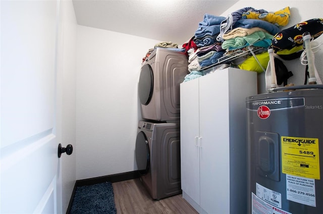 washroom featuring wood finished floors, water heater, and stacked washer / dryer