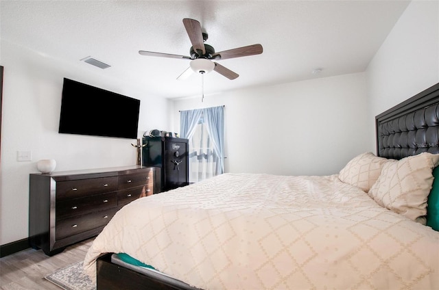 bedroom with baseboards, a ceiling fan, visible vents, and light wood-type flooring