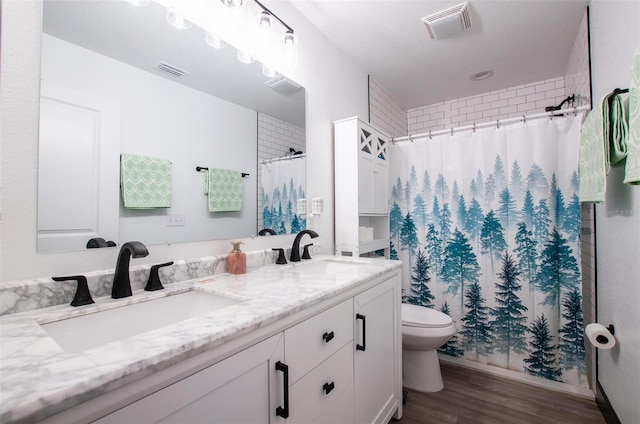 bathroom with wood finished floors, visible vents, and a sink