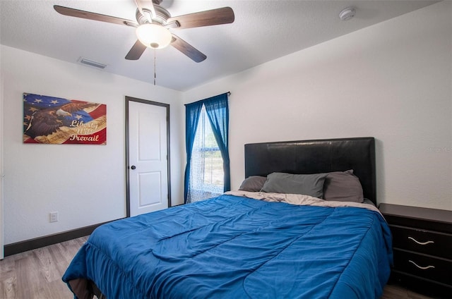 bedroom with visible vents, a ceiling fan, baseboards, and wood finished floors