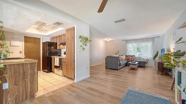 kitchen featuring visible vents, light wood-style floors, electric range, a textured ceiling, and a raised ceiling