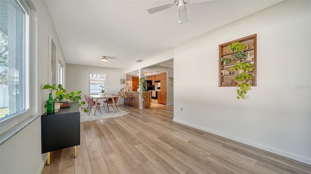 interior space featuring light wood-style flooring, a textured ceiling, and baseboards