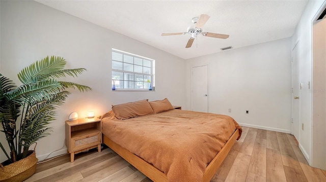 bedroom featuring visible vents, baseboards, light wood-style flooring, and a ceiling fan