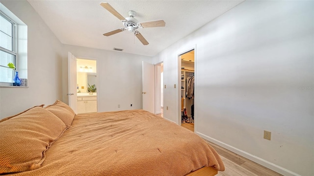 bedroom with a ceiling fan, visible vents, a spacious closet, light wood-style floors, and a closet