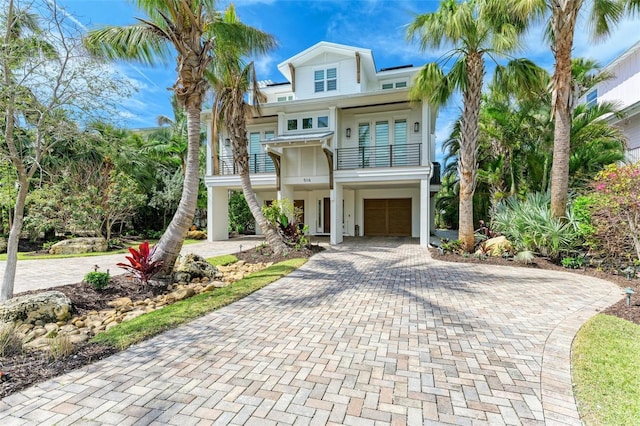 516 Kumquat Dr, Anna Maria, FL 34216 - raised beach house with a balcony, decorative driveway, stucco siding, a garage, and french doors
