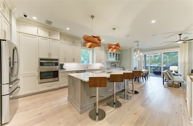 516 Kumquat Dr, Anna Maria, FL 34216 - kitchen featuring appliances with stainless steel finishes, light countertops, a kitchen bar, tasteful backsplash, and a kitchen island