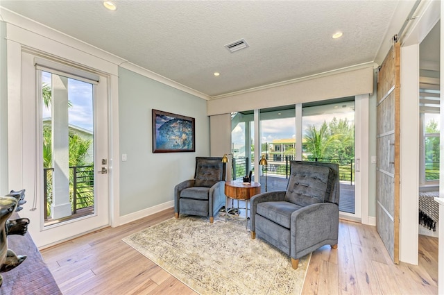 516 Kumquat Dr, Anna Maria, FL 34216 - sitting room with crown molding, a barn door, light wood-type flooring, healthy amount of natural light, and a textured ceiling