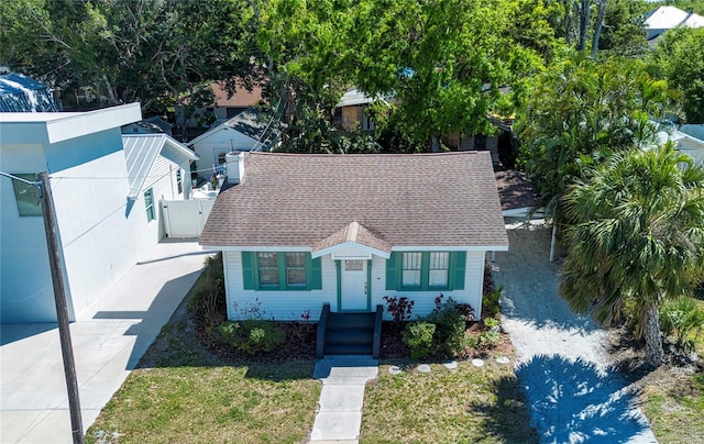 view of front of house with a front yard, roof with shingles, a gate, and fence