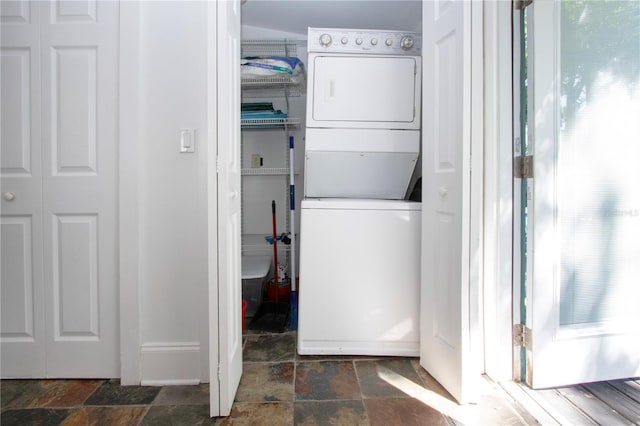 laundry room featuring stone tile flooring, stacked washer / drying machine, and laundry area