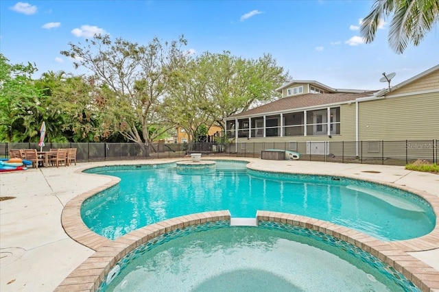 view of pool featuring a pool with connected hot tub, fence, outdoor dining area, a sunroom, and a patio area