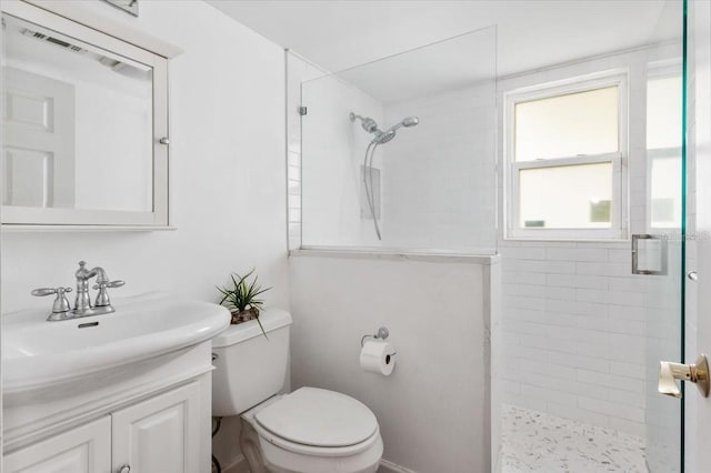 bathroom featuring vanity, toilet, and a tile shower