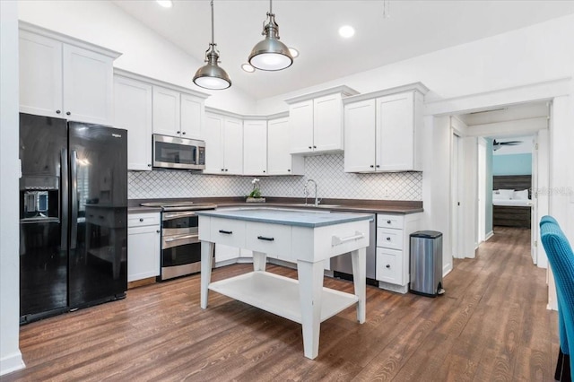 kitchen with dark countertops, dark wood-style floors, stainless steel appliances, and vaulted ceiling