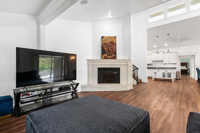 living room with plenty of natural light, a brick fireplace, and dark wood-type flooring