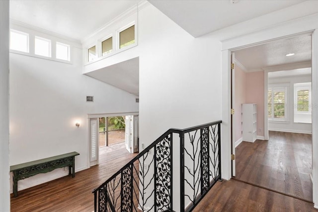 hallway featuring visible vents, an upstairs landing, a healthy amount of sunlight, and crown molding