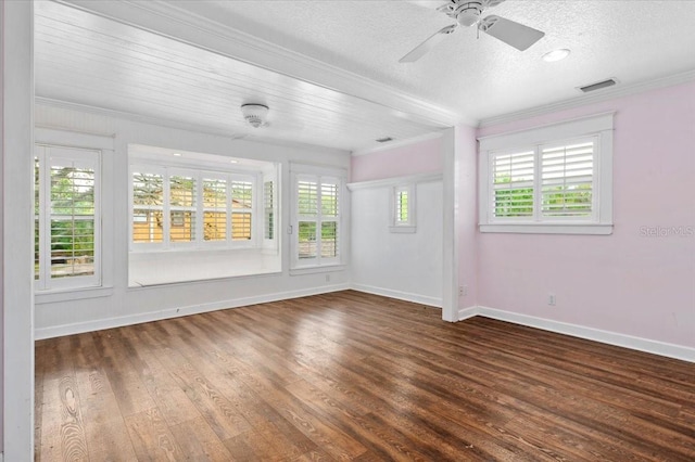 spare room with wood finished floors, visible vents, baseboards, a textured ceiling, and crown molding