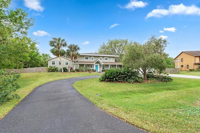 view of front of house featuring aphalt driveway, a front yard, and fence