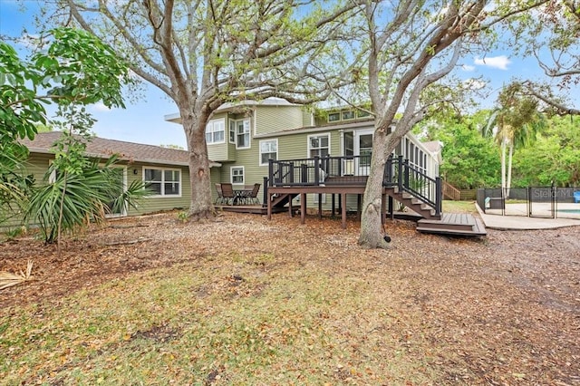 rear view of property with stairway, a wooden deck, and fence