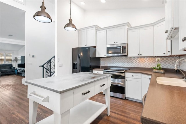 kitchen with dark wood-style flooring, a sink, stainless steel appliances, vaulted ceiling, and backsplash