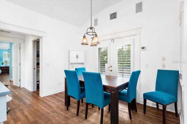 dining room with dark wood finished floors, visible vents, a chandelier, and lofted ceiling