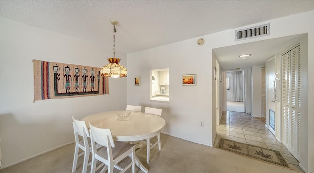 carpeted dining room with a textured ceiling, visible vents, and baseboards