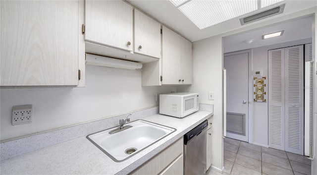 kitchen featuring a sink, visible vents, white microwave, dishwasher, and light countertops