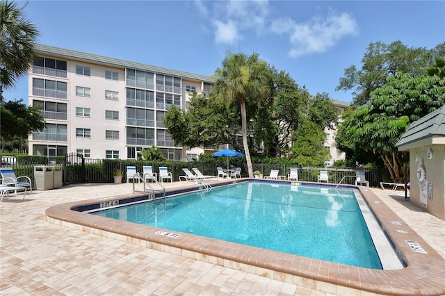 community pool with fence and a patio area