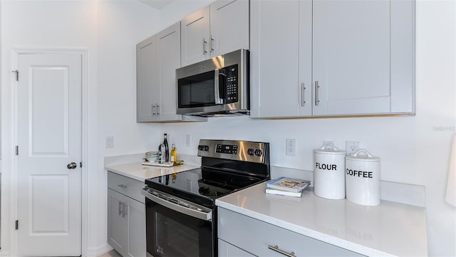 kitchen with light countertops, gray cabinets, and appliances with stainless steel finishes