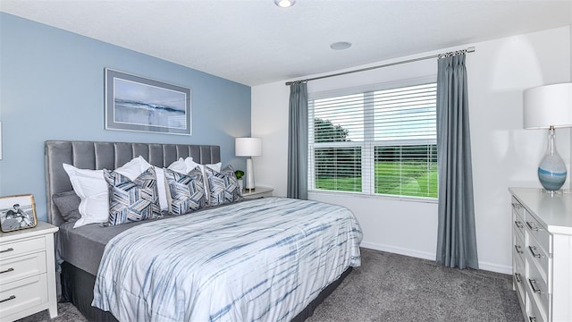 bedroom with dark colored carpet and baseboards