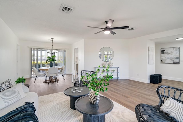 living room with visible vents, light wood finished floors, and ceiling fan with notable chandelier