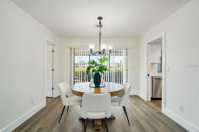 dining space featuring visible vents, baseboards, an inviting chandelier, and wood finished floors