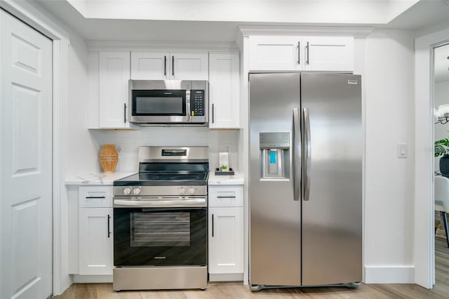 kitchen with baseboards, light wood finished floors, white cabinets, appliances with stainless steel finishes, and backsplash