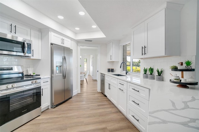 kitchen featuring a sink, light wood-type flooring, appliances with stainless steel finishes, and white cabinetry