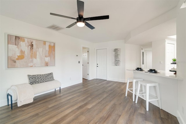 living area featuring visible vents, baseboards, wood finished floors, and a ceiling fan