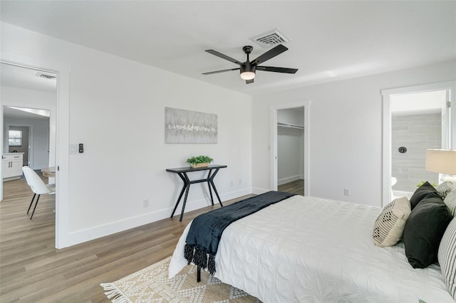 bedroom featuring a walk in closet, wood finished floors, visible vents, and baseboards