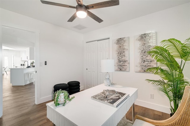 home office with ceiling fan, visible vents, baseboards, and wood finished floors