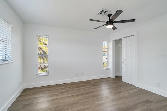 unfurnished bedroom with visible vents, baseboards, a closet, and wood finished floors