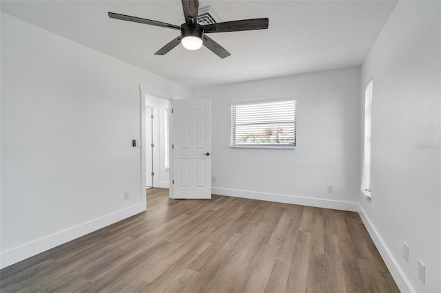 empty room featuring ceiling fan, baseboards, and wood finished floors