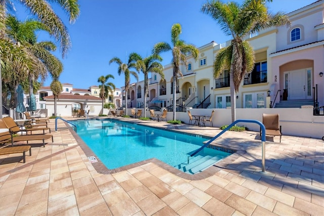 community pool with fence, a patio area, and a residential view