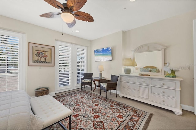 sitting room with a ceiling fan, baseboards, and light carpet