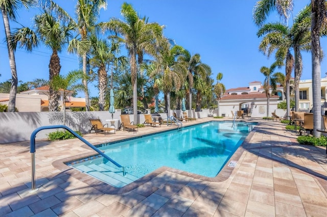 pool with a patio area and fence