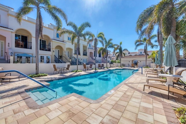 community pool featuring a residential view, fence, and a patio area