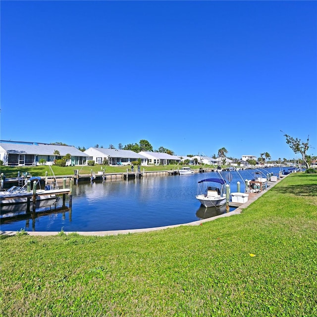 dock area with a residential view, a lawn, and a water view